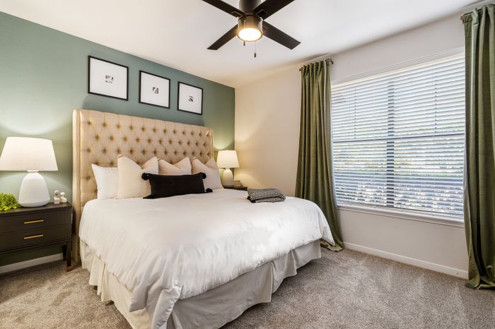 Elegant bedroom with a plush tufted headboard, stylish bedside lamps, and a large window with chic curtains, creating a cozy and luxurious ambiance.