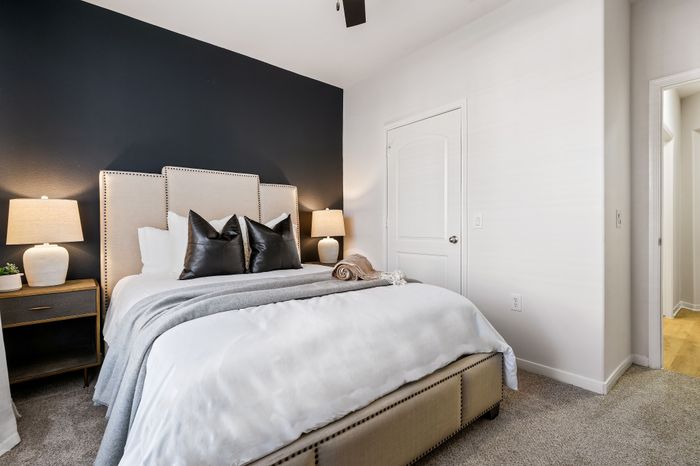 Elegant bedroom featuring a luxe bed with plush pillows, modern nightstands, and soft lighting against a stylish dark accent wall.