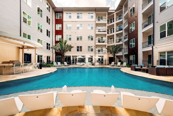 Luxurious apartment complex boasting a resort-style pool, sleek outdoor lounge, and modern architecture.