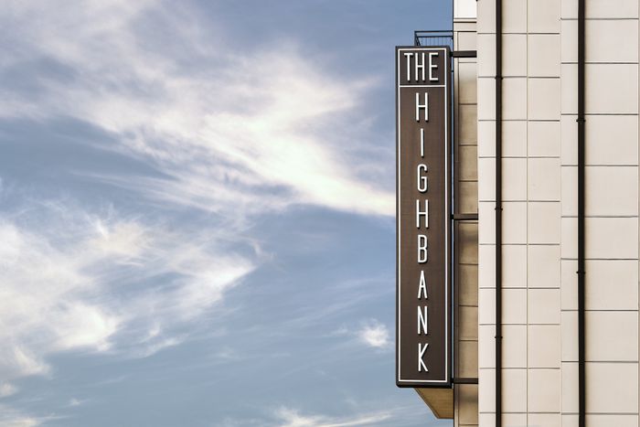 Elegant exterior view of The Highbank building, featuring modern architectural design against a vibrant blue sky.