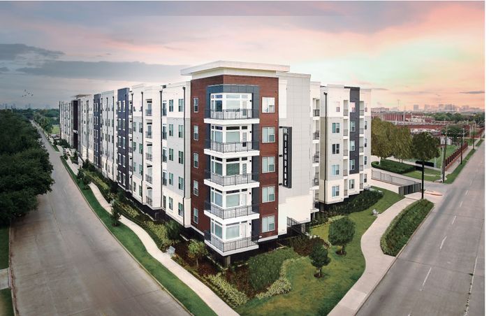 Modern, multi-story apartment complex with sleek design and lush landscaping in a vibrant urban setting.