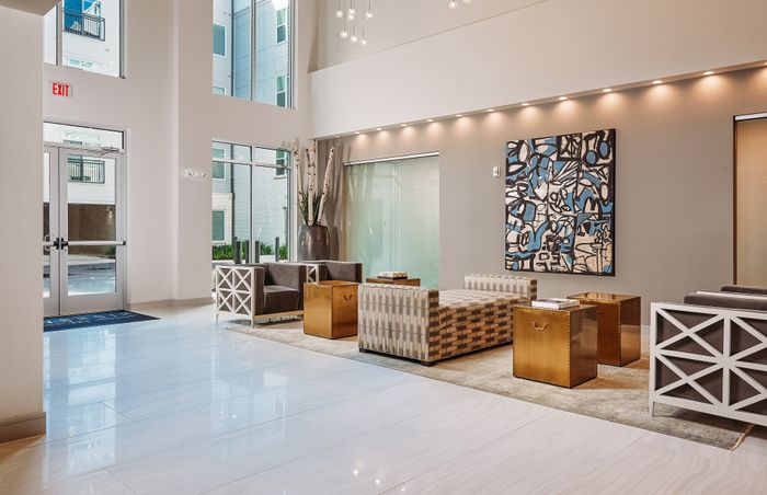 Elegant apartment lobby with modern seating, stylish artwork, and large windows for natural light.
