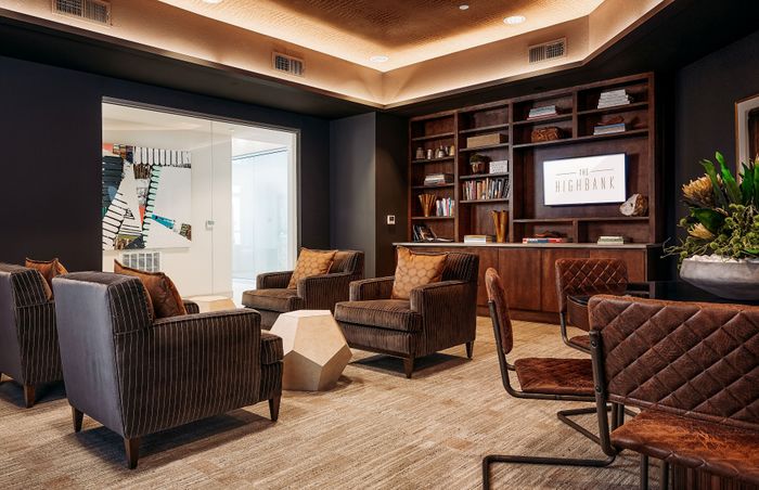 Elegant lounge area featuring plush seating, modern art, and a stylish bookcase in a luxurious apartment.
