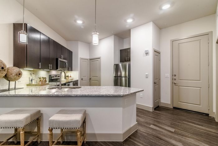 Modern kitchen with sleek granite countertops, stainless steel appliances, and stylish dark wood cabinets, featuring an elegant open layout.