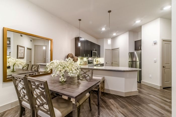 Chic modern kitchen with sleek countertops, stainless steel appliances, and elegant dining area adorned with fresh flowers.