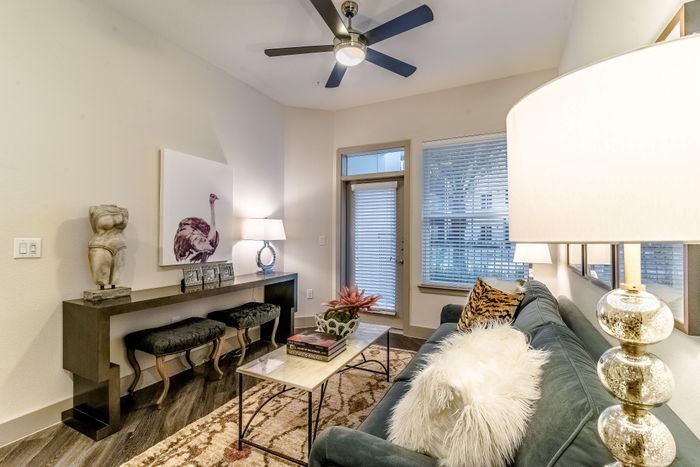 Chic living room with modern decor, featuring a plush blue sofa, artistic sculptures, stylish coffee table, and elegant lighting.