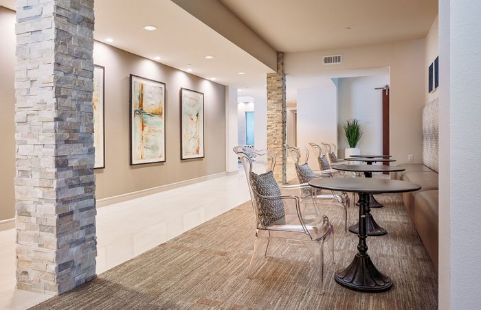 Sleek modern lounge area with stylish transparent chairs, stone accent columns, and contemporary artwork on the walls.