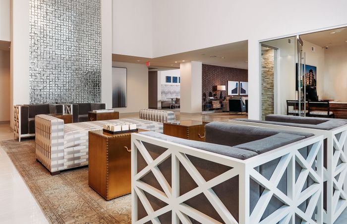 Luxurious modern apartment lobby with elegant seating, stylish decor, and contemporary artwork, offering a welcoming atmosphere.