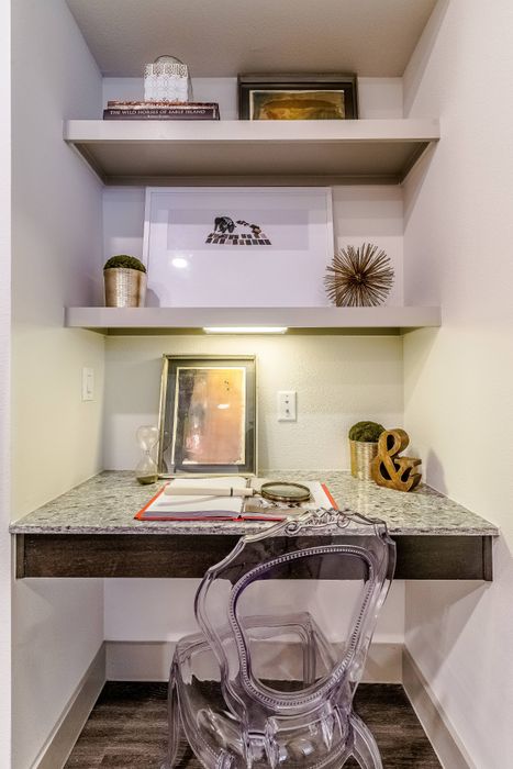 Chic home office nook with stylish glass chair, elegant shelving, and modern decor accents.