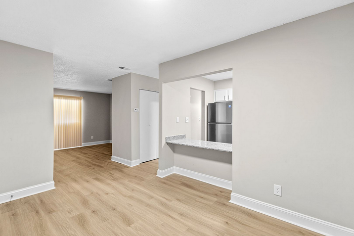 Bright and modern apartment interior with sleek laminate flooring, an inviting open-concept layout, and a stylish kitchen area with stainless steel appliances.