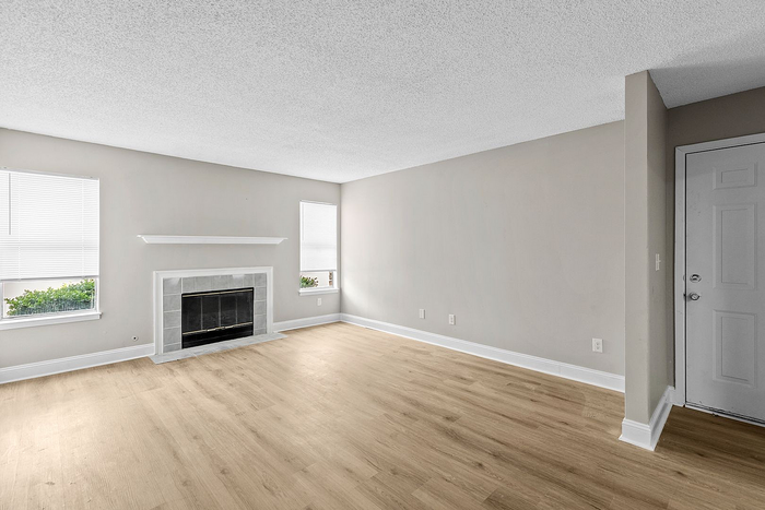 Bright and spacious living room with elegant fireplace, large windows, and sleek hardwood floors.