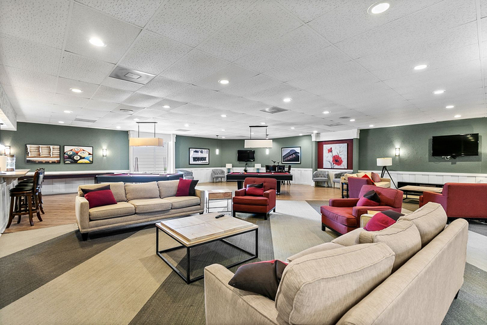 Spacious and inviting entertainment room with modern lounge seating, a pool table, and vibrant decor accents.