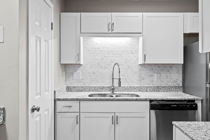 Modern kitchen featuring sleek white cabinets, granite countertops, and a contemporary stainless steel faucet.