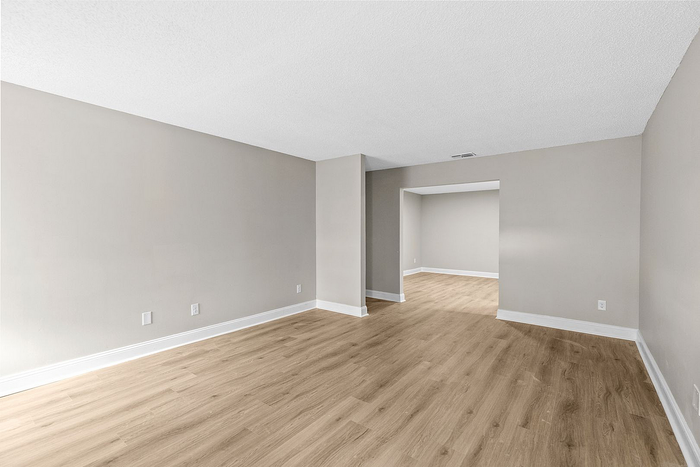 Bright and spacious open-plan apartment interior featuring elegant hardwood floors and modern neutral walls.
