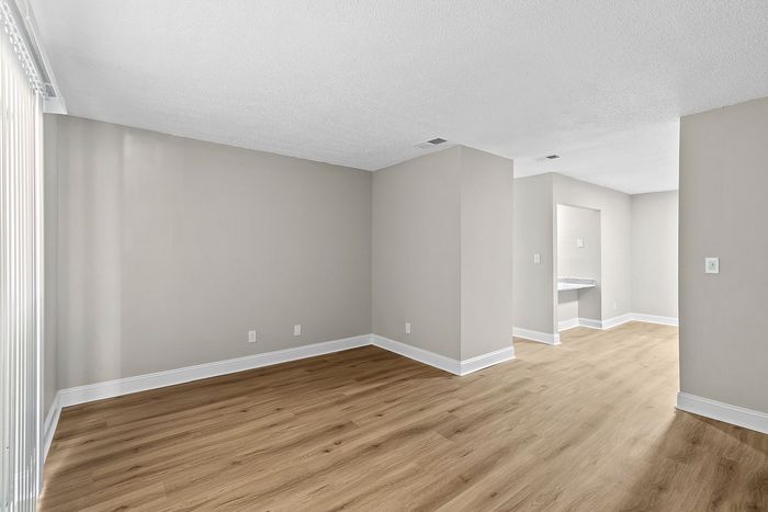 Bright and airy living space featuring sleek wood flooring and neutral walls, perfect for modern living.