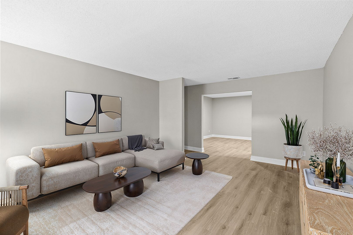 Elegant living room with a modern beige sectional sofa, chic abstract wall art, and stylish wooden accents, complemented by light wood flooring and natural décor.
