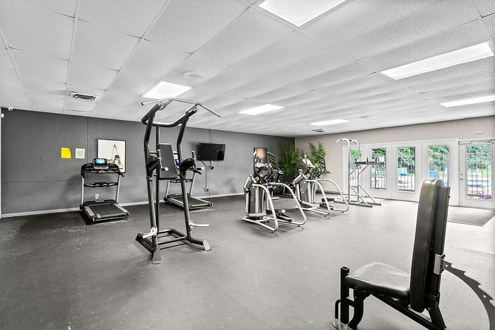 Modern fitness center featuring state-of-the-art cardio equipment and a view of the pool through large windows.