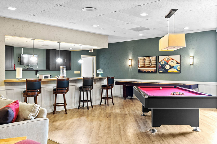 Chic recreational lounge featuring a stylish bar with high stools, modern lighting, and a vibrant pool table, perfect for entertainment and relaxation.