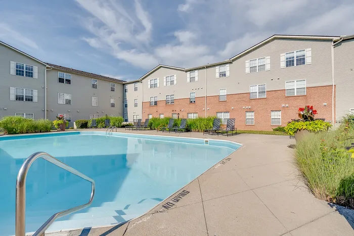 Inviting apartment complex with a sparkling outdoor pool, surrounded by lush greenery and modern architecture.