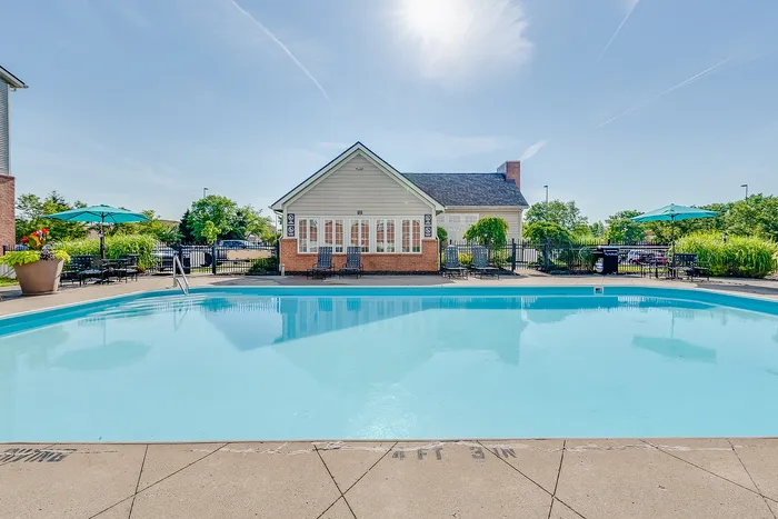Inviting outdoor pool area with sun loungers and lush greenery, perfect for relaxation and leisure.