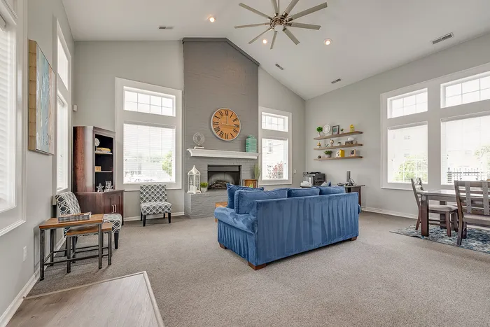 Bright and airy living room with high ceilings, modern fireplace, and elegant decor including a plush blue sofa and stylish shelving.
