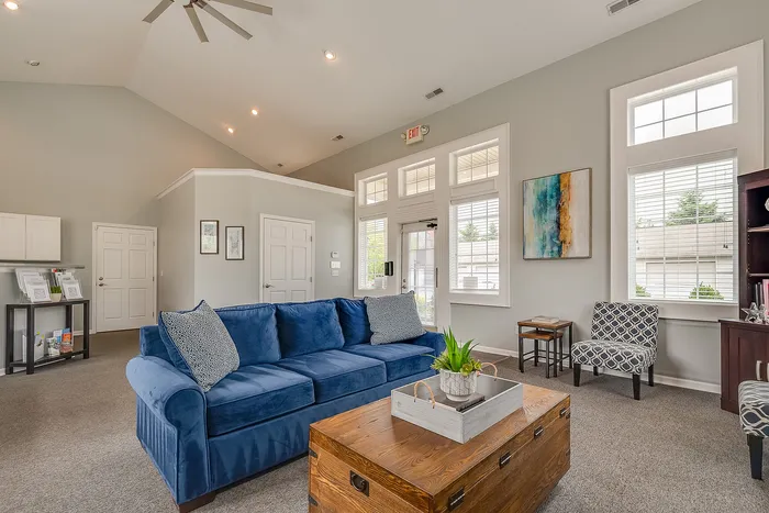 Inviting living room with high ceilings, plush blue sofa, and natural light from large windows, creating a cozy and stylish ambiance.