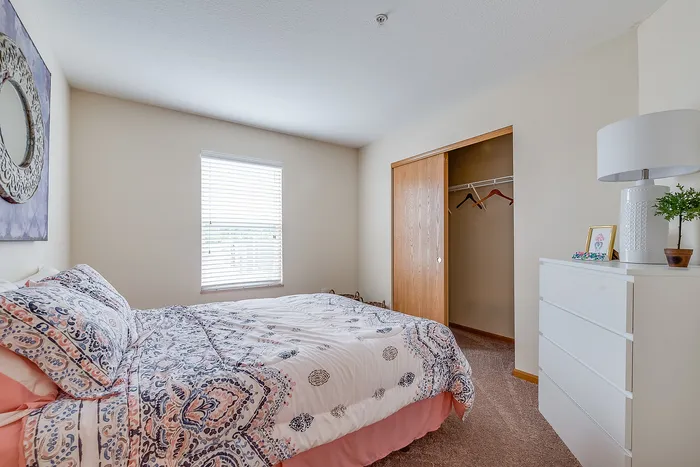 Inviting bedroom with plush bedding, natural light from a window, and a spacious closet, offering comfort and relaxation.