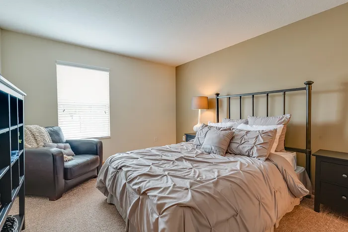 Inviting bedroom with plush bedding, cozy seating, and abundant natural light, ideal for relaxation and comfort.