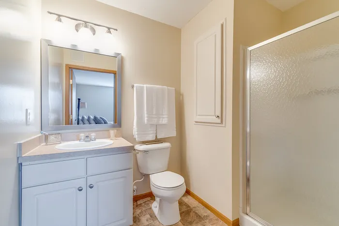 Bright and inviting bathroom featuring modern fixtures, a sleek glass shower, and elegant tile flooring.