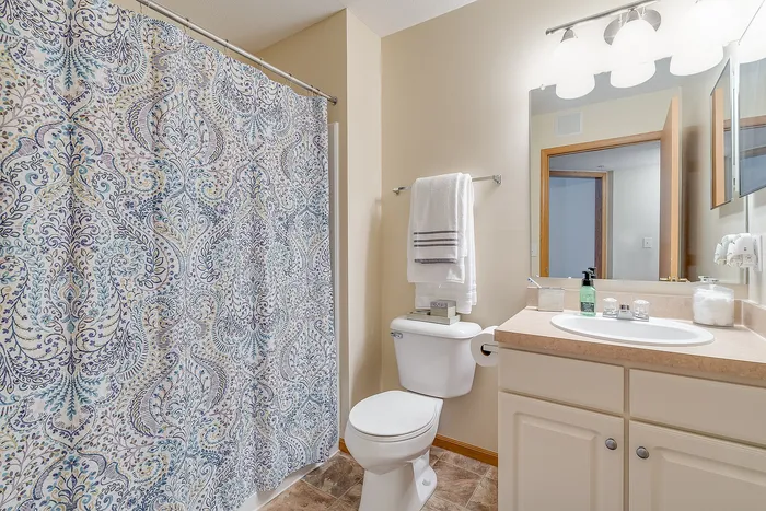 Bright and inviting bathroom with elegant paisley shower curtain, clean white amenities, and ample lighting for a refreshing ambiance.
