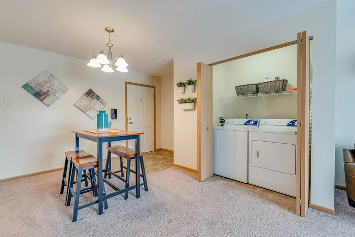 Inviting dining area with cozy table and chairs, adjacent to a convenient in-unit laundry setup with washer and dryer, accentuated by modern decor.