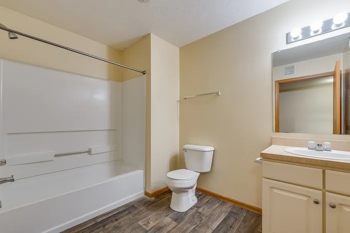Inviting bathroom showcasing a sleek white bathtub, modern fixtures, and a large vanity mirror, blending functionality with style.