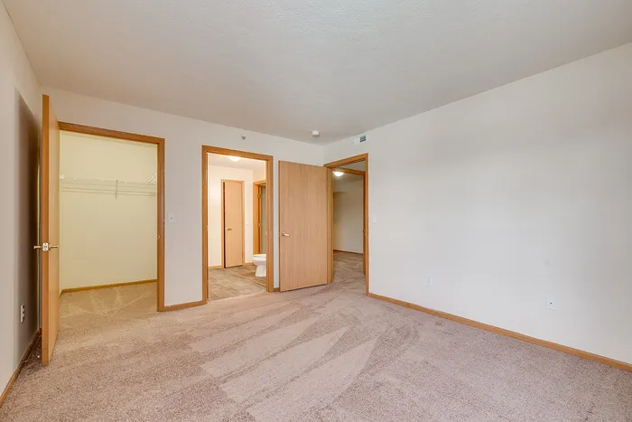 Spacious and inviting bedroom with plush carpet, featuring a large walk-in closet and en-suite bathroom.