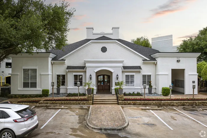 Charming apartment building exterior featuring elegant white facade, lush landscaping, and a welcoming entrance, perfect for modern living.