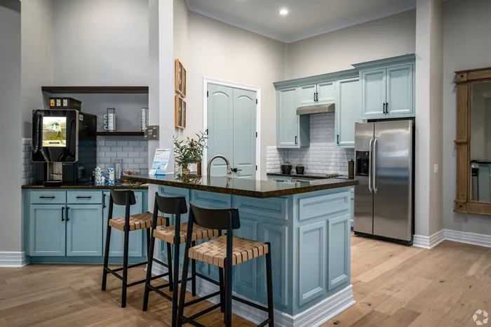 Chic kitchen with modern blue cabinetry, stainless steel appliances, and stylish bar stools on hardwood floors.