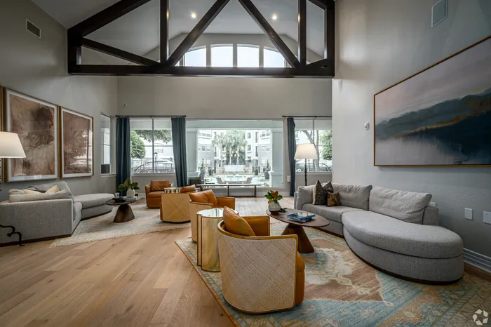 Elegant living room with vaulted ceilings, modern furnishings, and a large window offering a scenic courtyard view.