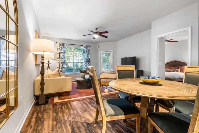 Inviting living and dining area with stylish décor, featuring a cozy beige sofa, a wooden dining table, and large windows for natural light.
