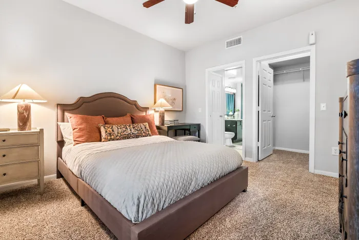 Inviting bedroom with plush carpet, stylish bed with decorative pillows, and a modern ensuite bathroom.