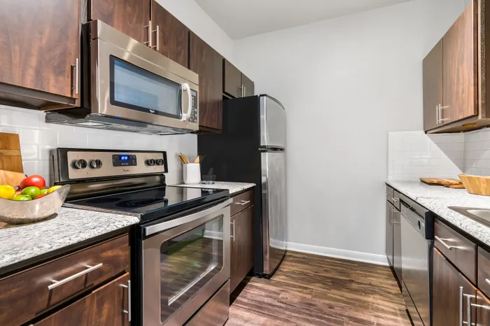Modern kitchen with sleek stainless steel appliances, elegant granite countertops, and rich wood cabinetry, perfect for culinary enthusiasts.