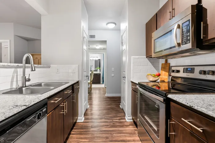 Modern kitchen with sleek stainless steel appliances, granite countertops, and elegant wooden cabinetry, perfect for stylish living.