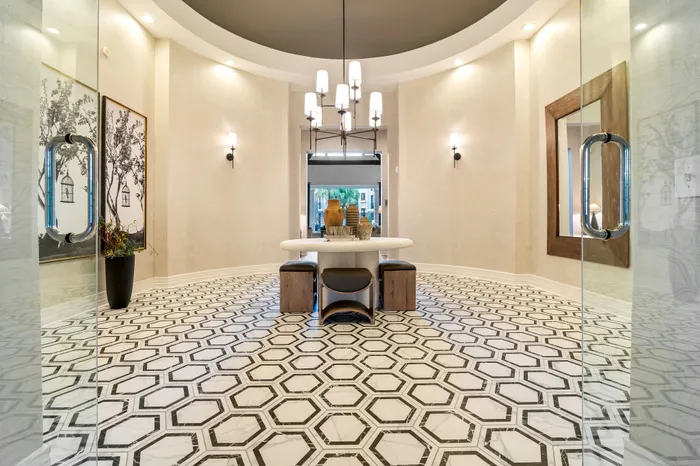 Elegant lobby entrance with striking geometric marble flooring, contemporary chandelier, and stylish decor.