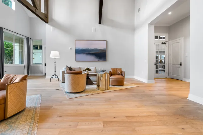 Spacious living room with elegant hardwood floors, stylish leather chairs, and large windows offering natural light.