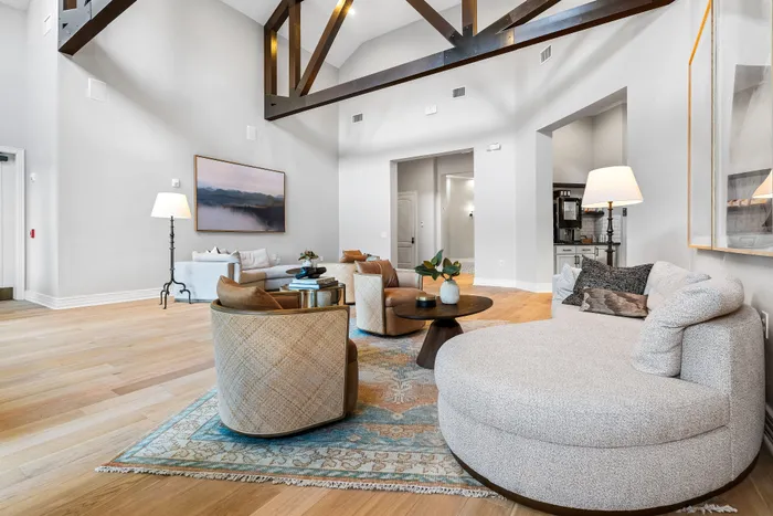 Elegant living room with high ceilings, exposed wooden beams, cozy seating, and stylish decor.