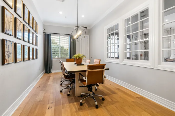 Bright and elegant dining room with sleek wooden flooring, modern leather chairs, and abundant natural light.