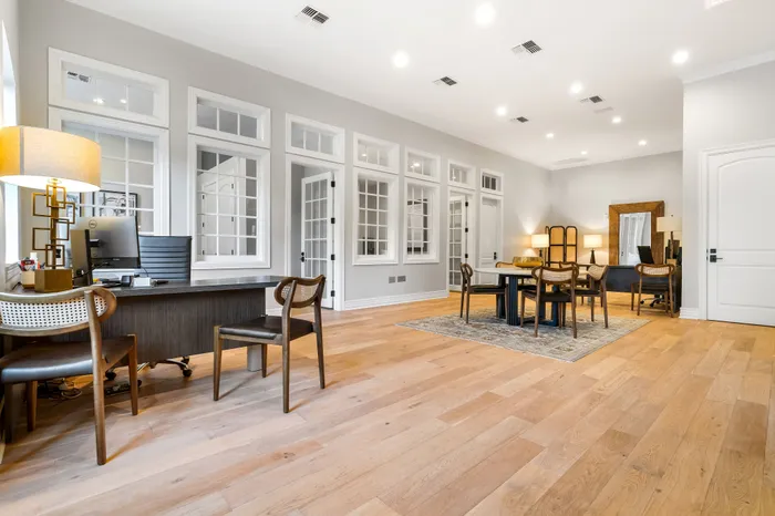 Elegant open-concept office space featuring modern wood flooring, stylish furniture, and ample natural light.