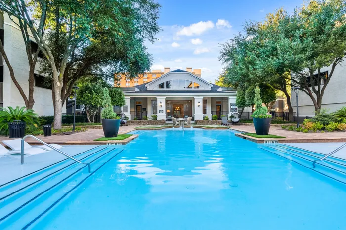 Luxurious apartment complex with a sparkling outdoor pool, surrounded by lush greenery and elegant architecture.