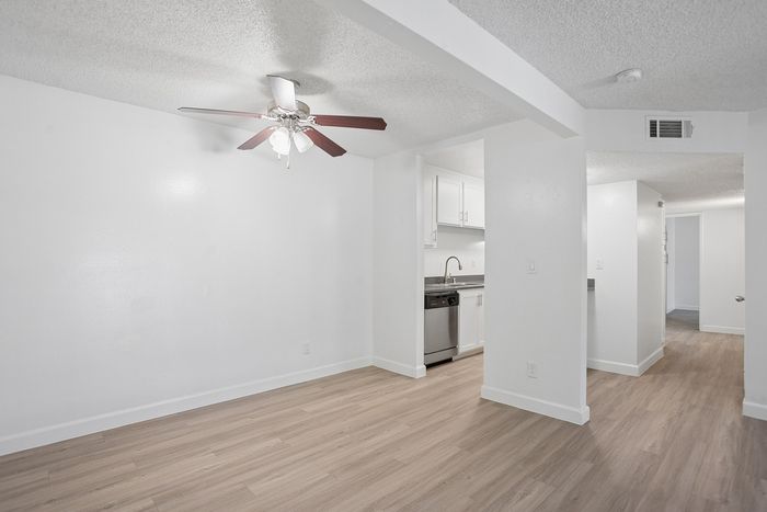 Bright open-plan living area with modern kitchen, elegant ceiling fan, and sleek hardwood floors.