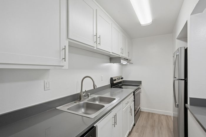 Sleek modern kitchen with stainless steel appliances, elegant white cabinetry, and a chic gray countertop.
