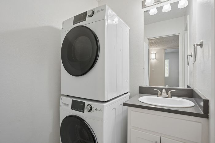 Modern bathroom with elegant sink and convenient stacked washer and dryer unit.