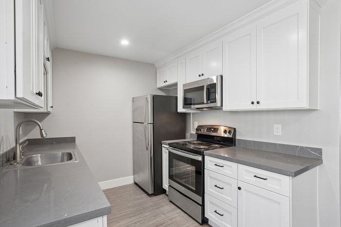 Modern kitchen with sleek stainless steel appliances, elegant white cabinetry, and polished gray countertops.